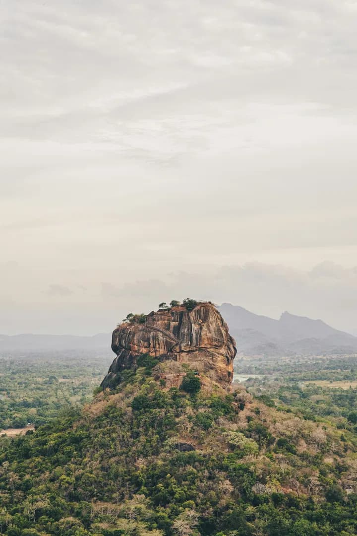 Massive red rock formation rising from tropical forest