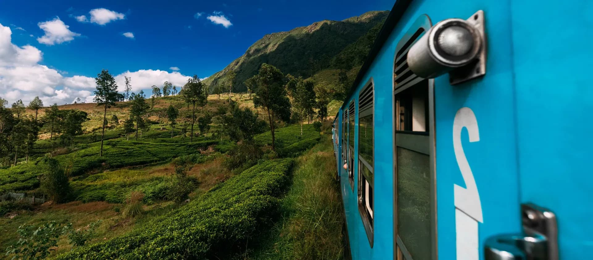 Blue train traveling through Sri Lanka's scenic hill country