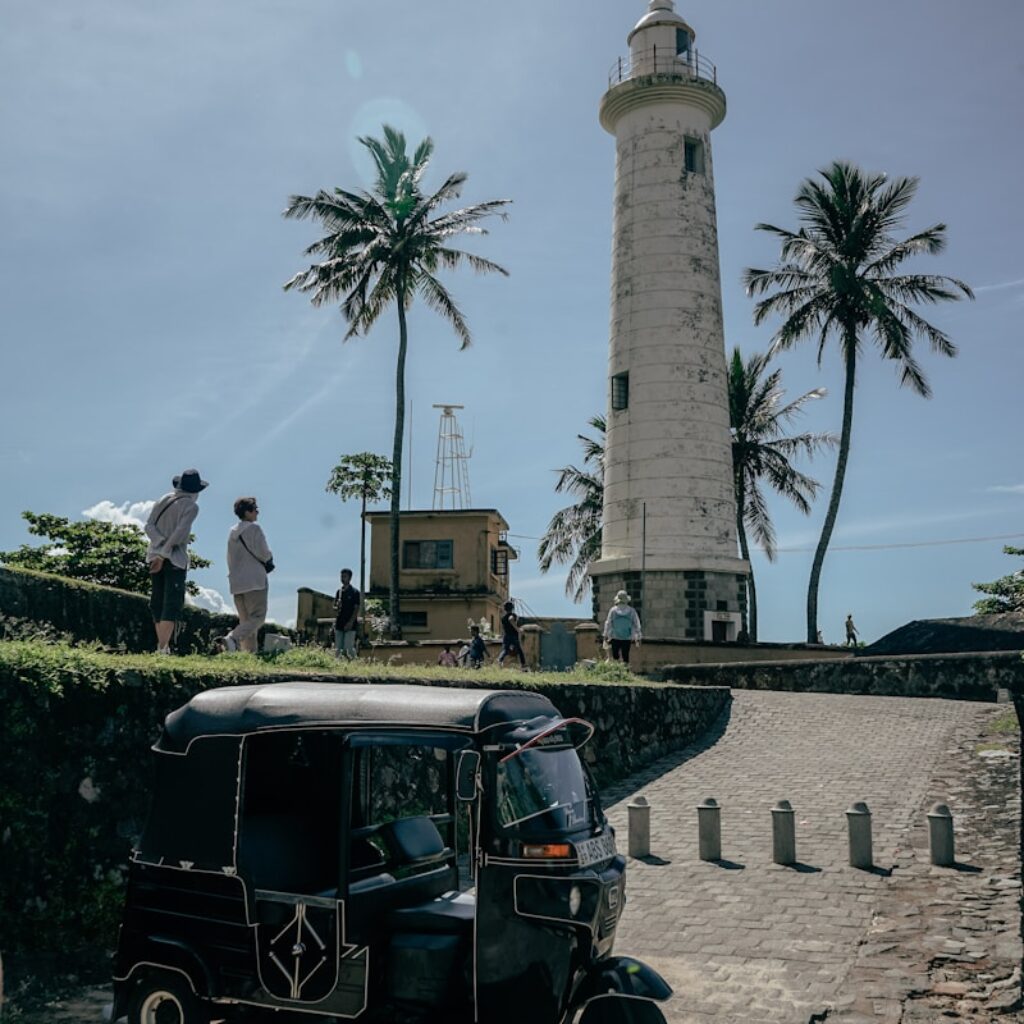 a tuk tuk parked in front of a lighthouse