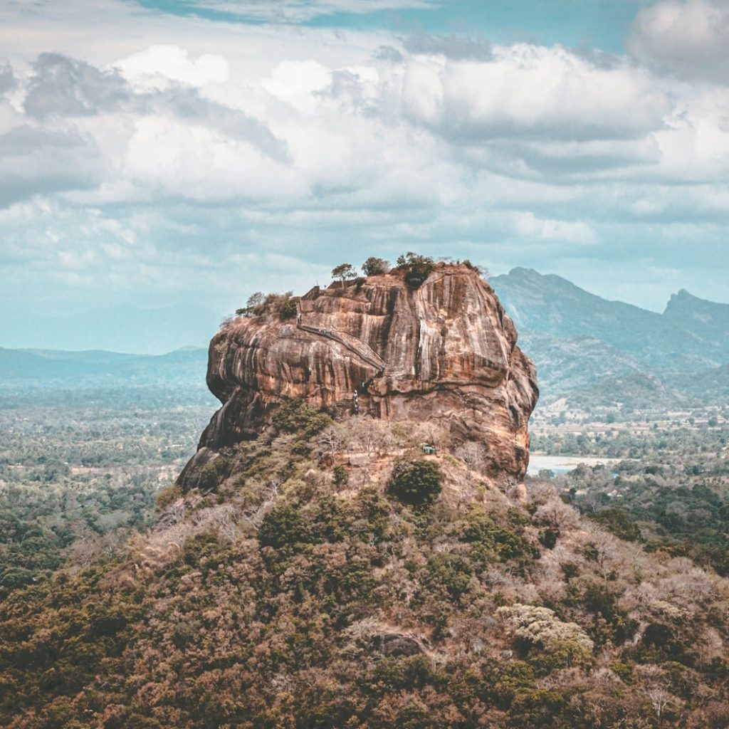 brown rock formation under white clouds during daytime